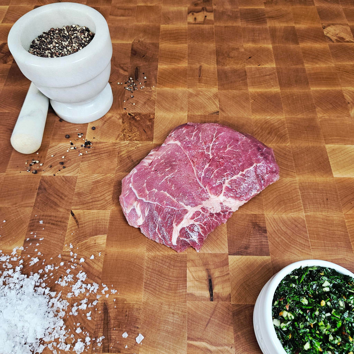 Grass-fed beef sirloin tip steak on an end-grain butcher block with flake salt, cracked pepper, and chimichurri — Wishbone Heritage Farms, Saint George, SC