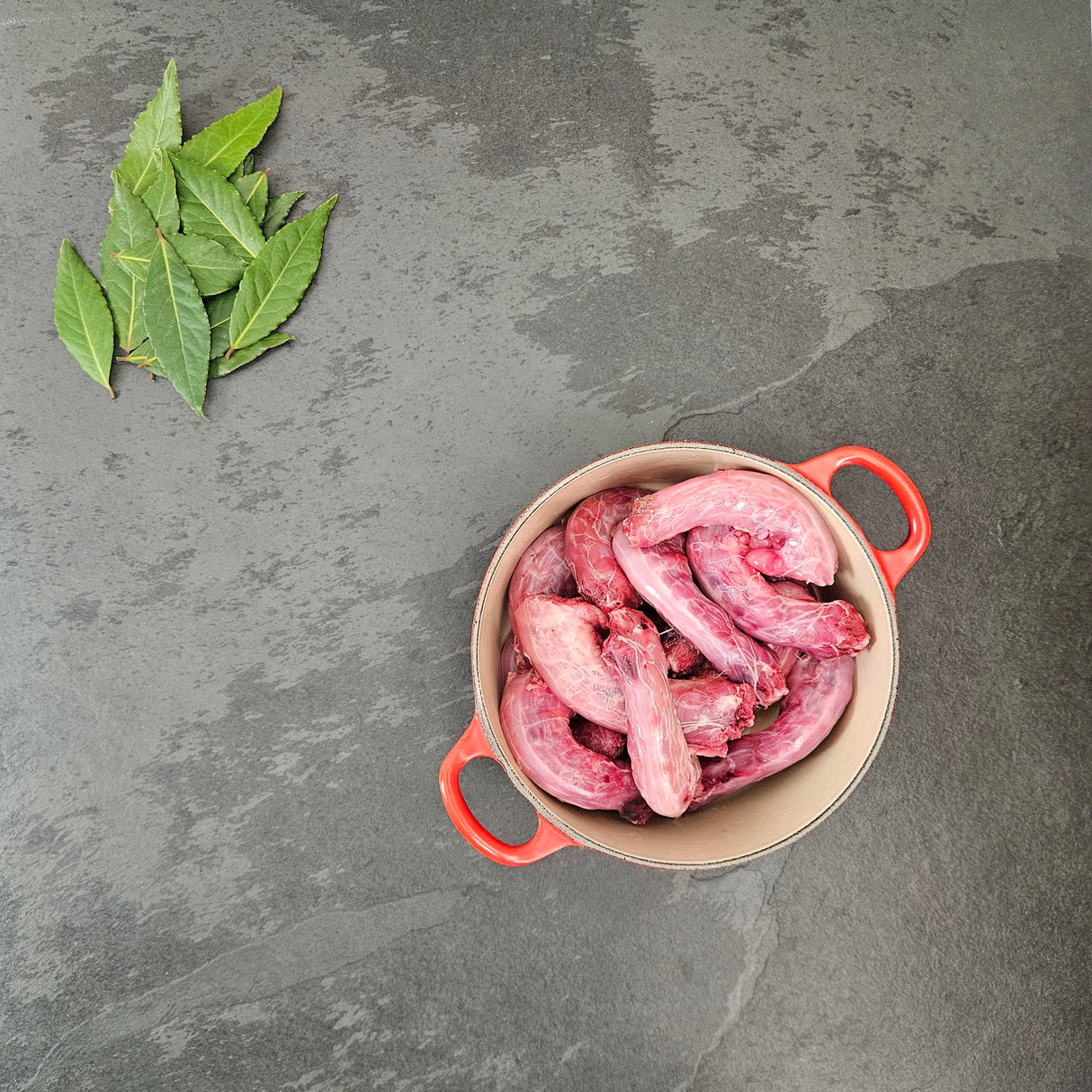 Pasture-raised chicken necks in a red Le Creuset Dutch oven with fresh bay leaves — Wishbone Heritage Farms, Saint George, SC