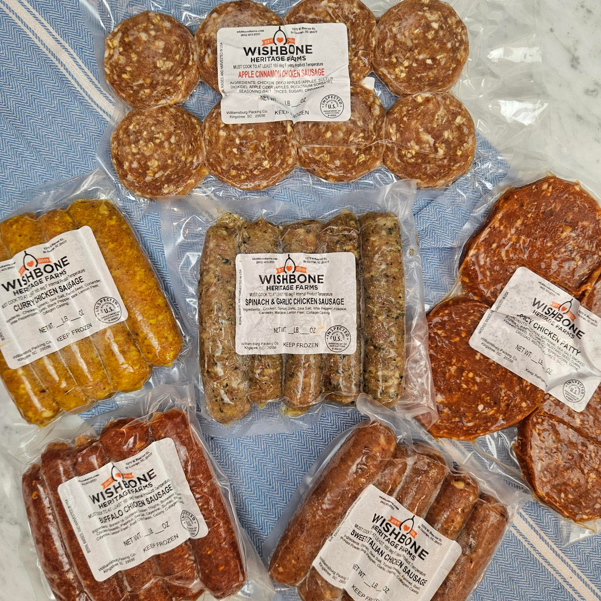 Wishbone Heritage Farms pasture-raised chicken sausage bundle — apple cinnamon, curry, spinach garlic, buffalo, sweet Italian, and spicy chicken patties in vacuum-sealed packaging — Saint George, SC