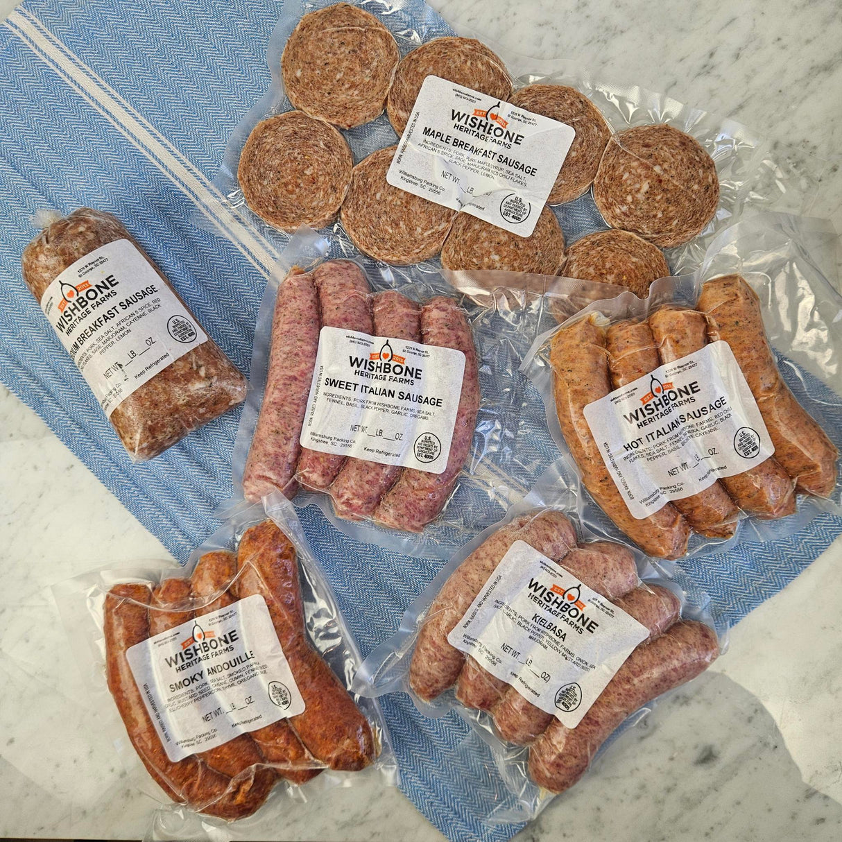 Wishbone Heritage Farms pasture-raised heritage pork sausage bundle — maple breakfast, sweet Italian, hot Italian, smoky andouille, kielbasa, and pork breakfast sausage in vacuum-sealed packaging — Saint George, SC