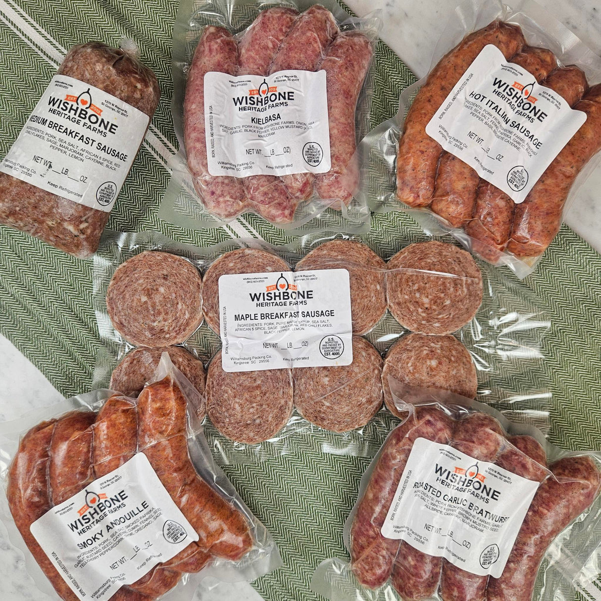 Wishbone Heritage Farms pasture-raised heritage pork sausage bundle — maple breakfast, sweet Italian, hot Italian, smoky andouille, kielbasa, and pork breakfast sausage in vacuum-sealed packaging — Saint George, SC