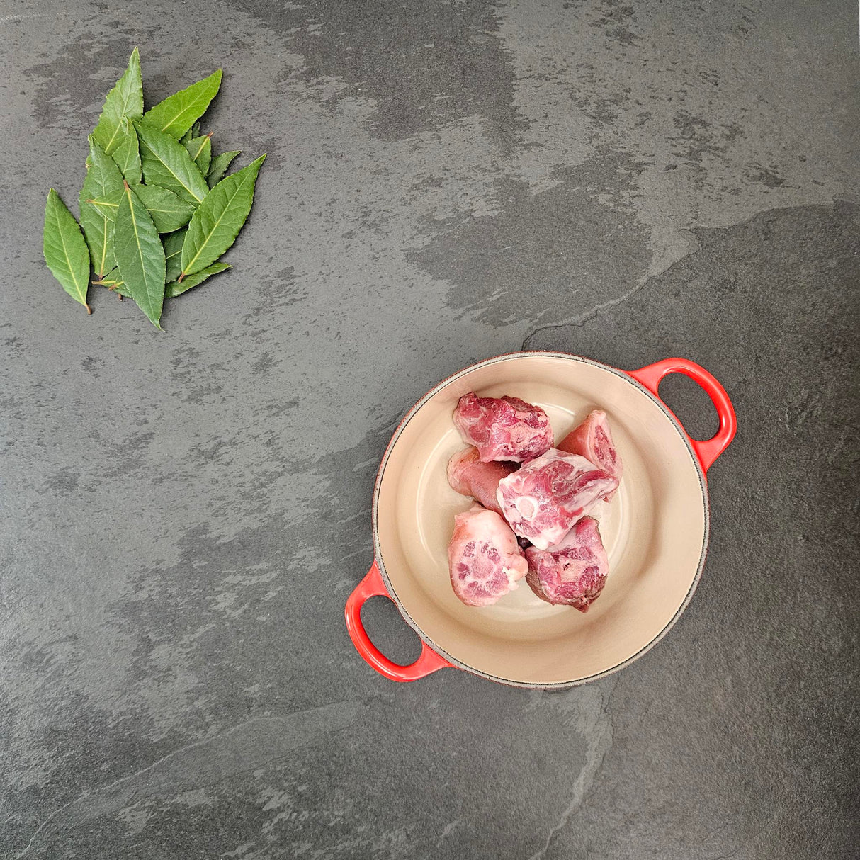 Pasture-raised heritage breed pork pig tail in a red Le Creuset Dutch oven with fresh bay leaves — Wishbone Heritage Farms, Saint George, SC