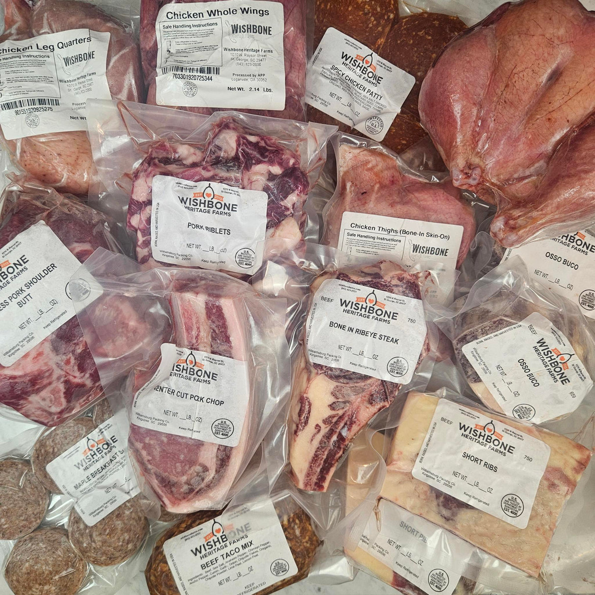 Wishbone Heritage Farms bone-in ultimate value bundle — chicken leg quarters, whole wings, spicy chicken patties, pork riblets, bone-in skin-on chicken thighs, center cut pork chop, bone-in ribeye steak, short ribs, osso buco, pork shoulder butt, maple breakfast sausage, and beef taco mix in vacuum-sealed packaging — Saint George, SC