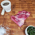Grass-fed beef bavette steak on an end-grain butcher block with flake salt, cracked pepper, and chimichurri — Wishbone Heritage Farms, Saint George, SC