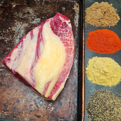 Grass-fed beef brisket on a seasoned sheet pan with dry rub spices — brown sugar, paprika, mustard, and black pepper — Wishbone Heritage Farms, Saint George, SC
