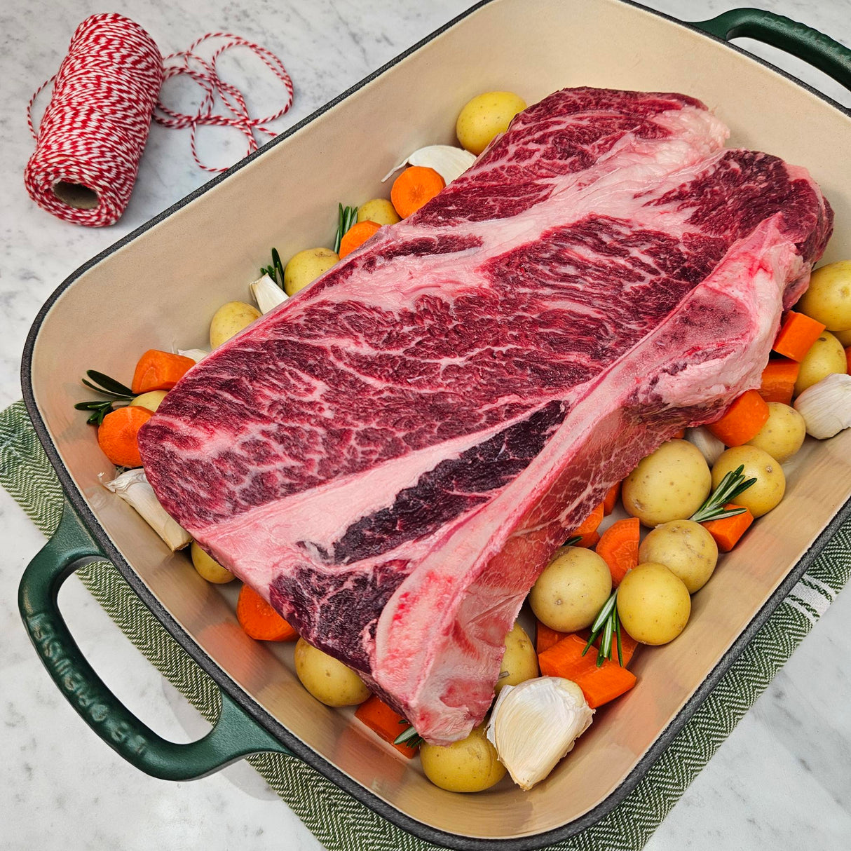 Grass-fed beef chuck roast in a green Le Creuset roasting pan with potatoes, carrots, garlic, and rosemary — Wishbone Heritage Farms, Saint George, SC