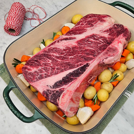 Grass-fed beef chuck roast in a green Le Creuset roasting pan with potatoes, carrots, garlic, and rosemary — Wishbone Heritage Farms, Saint George, SC