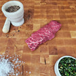 Grass-fed beef Denver steak on an end-grain butcher block with flake salt, cracked pepper, and chimichurri — Wishbone Heritage Farms, Saint George, SC