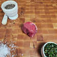 Grass-fed beef filet mignon on an end-grain butcher block with flake salt, cracked pepper, and chimichurri — Wishbone Heritage Farms, Saint George, SC