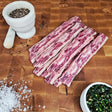 Grass-fed beef flanken style short ribs on an end-grain butcher block with flake salt, cracked pepper, and chimichurri — Wishbone Heritage Farms, Saint George, SC