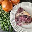 Grass-fed beef heart on a white plate with fresh rosemary and yellow onions — Wishbone Heritage Farms, Saint George, SC