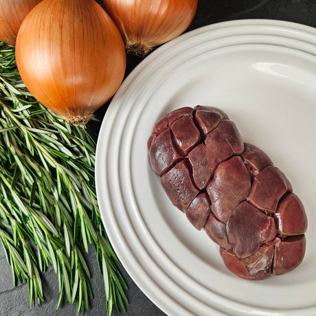 Grass-fed beef kidney on a white plate with fresh rosemary and yellow onions — Wishbone Heritage Farms, Saint George, SC