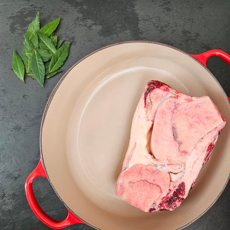 Grass-fed beef knuckle bones in a red Le Creuset Dutch oven with fresh bay leaves — Wishbone Heritage Farms, Saint George, SC