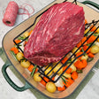 Grass-fed beef rump roast in a green Le Creuset roasting pan with potatoes, carrots, garlic, rosemary, and butcher's twine — Wishbone Heritage Farms, Saint George, SC