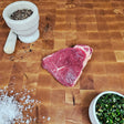 Grass-fed beef sirloin steak on an end-grain butcher block with flake salt, cracked pepper, and chimichurri — Wishbone Heritage Farms, Saint George, SC