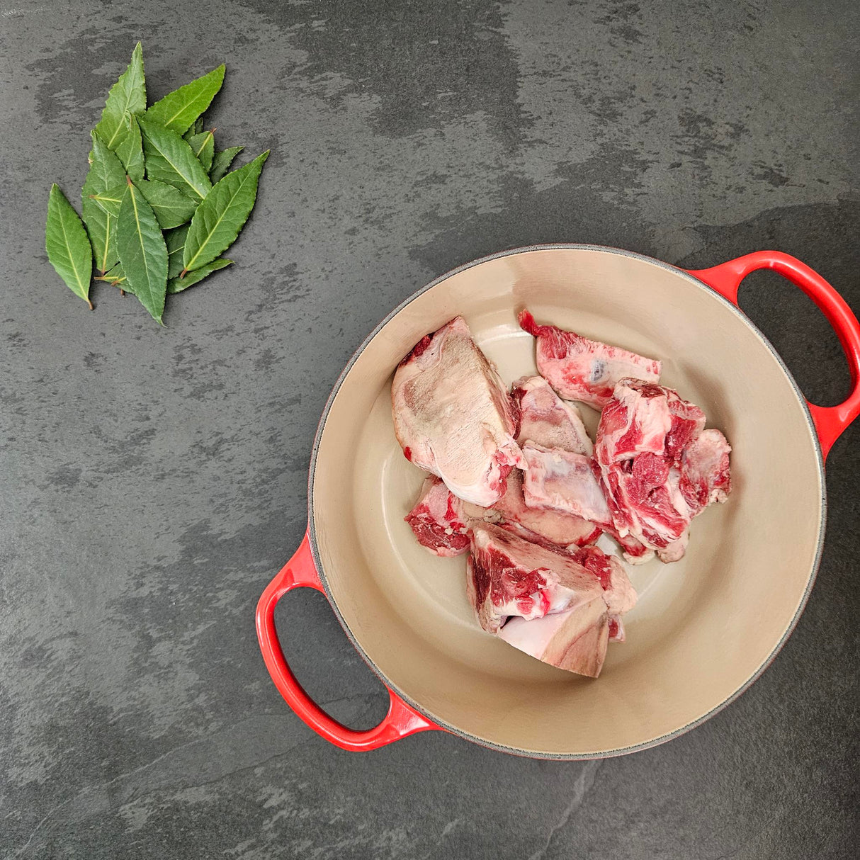 Grass-fed beef soup bones in a red Le Creuset Dutch oven with fresh bay leaves — Wishbone Heritage Farms, Saint George, SC