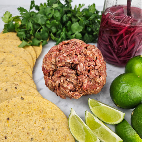 Grass-fed beef taco mix on white marble with corn tortillas, fresh cilantro, pickled red onions, and lime wedges — Wishbone Heritage Farms, Saint George, SC