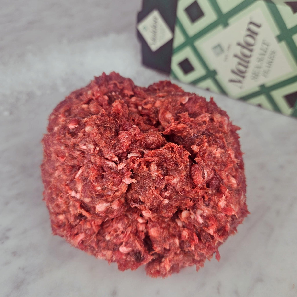 Fresh grass-fed ground beef with organs on white marble with Maldon sea salt — Wishbone Heritage Farms, South Carolina