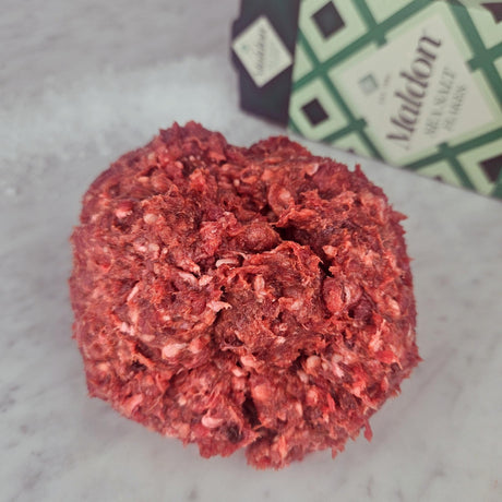 Fresh grass-fed ground beef with organs on white marble with Maldon sea salt — Wishbone Heritage Farms, South Carolina