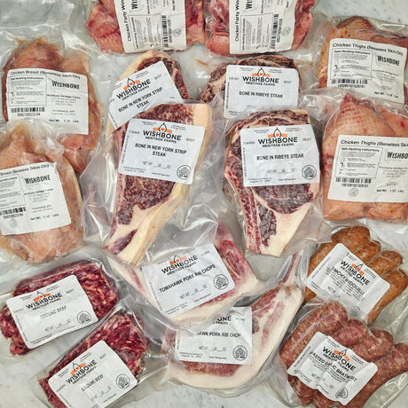 Wishbone Heritage Farms Grill Master's Dream Bundle — bone-in NY strip steaks, bone-in ribeye steaks, tomahawk pork rib chops, chicken wings, boneless skin-on chicken breasts, boneless skin-on chicken thighs, ground beef, smoky andouille, and roasted garlic bratwurst in vacuum-sealed packaging — Saint George, SC