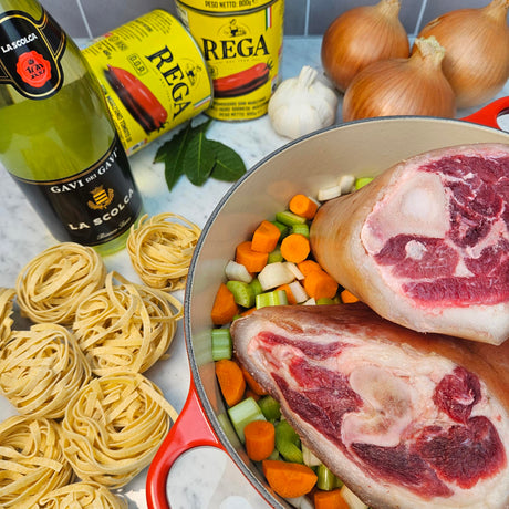 Raw pasture-raised heritage pork fresh ham hocks on carrots, celery, and onion in a red Dutch oven with Gavi white wine, San Marzano tomatoes, bay leaves, garlic, and tagliatelle nests for ragù prep — Wishbone Heritage Farms, Saint George, SC