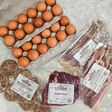 Breakfast Variety Pack on white marble — pasture-raised eggs, uncured smoked bacon, maple breakfast sausage patties, and grass-fed sirloin tip steak — Wishbone Heritage Farms, South Carolina