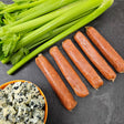 Raw pasture-raised buffalo chicken sausage links on dark slate with fresh celery and blue cheese — Wishbone Heritage Farms, South Carolina