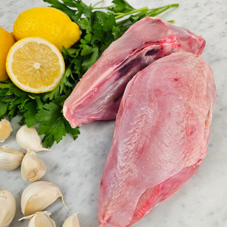 Raw pasture-raised bone-in chicken breasts on white marble with lemon, garlic, and fresh parsley — Wishbone Heritage Farms, South Carolina