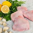 Raw pasture-raised bone-in skin-on chicken thighs on white marble with lemon, garlic, and fresh parsley — Wishbone Heritage Farms, South Carolina