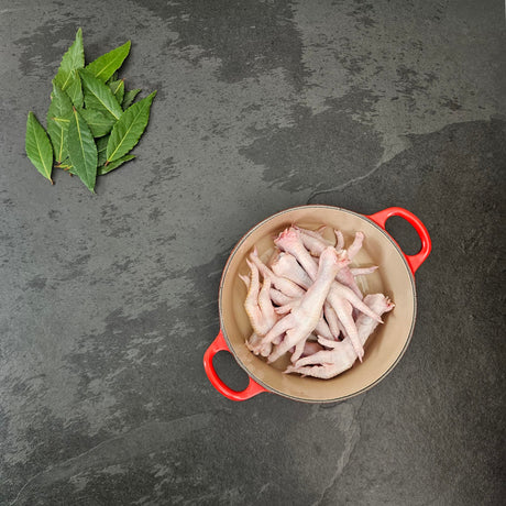 Pasture-raised chicken feet in a red Le Creuset Dutch oven with fresh bay leaves — Wishbone Heritage Farms, Saint George, SC