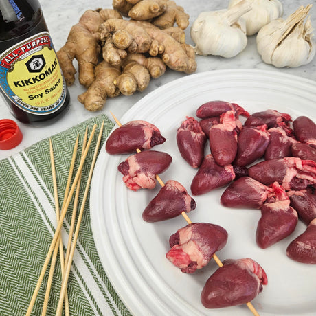 Pasture-raised chicken hearts on skewers and a white plate with fresh ginger, garlic, soy sauce, and bamboo skewers — Wishbone Heritage Farms, Saint George, SC