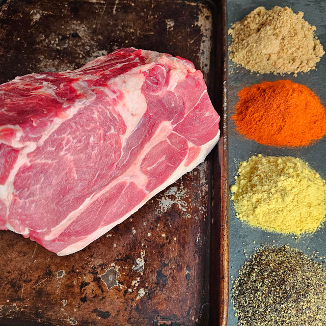 Pasture-raised heritage breed pork Boston butt on a seasoned sheet pan with dry rub spices — brown sugar, paprika, mustard, and black pepper — Wishbone Heritage Farms, Saint George, SC
