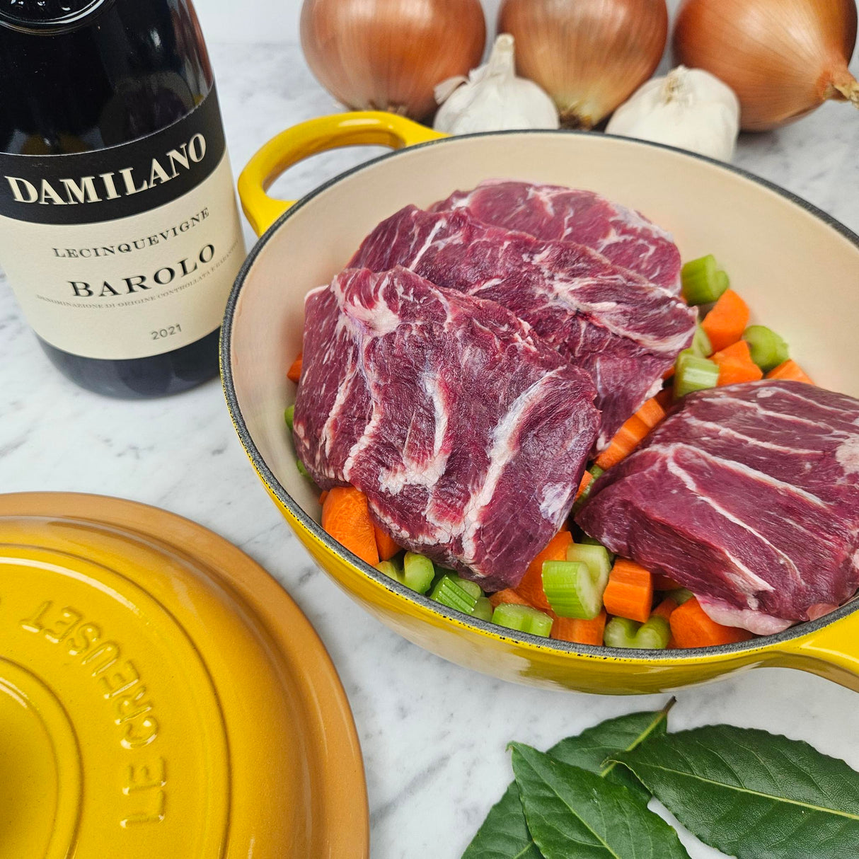 Pasture-raised heritage pork cheeks brasato prep in a yellow Le Creuset Dutch oven with carrots, celery, onions, bay leaves, and Barolo — Wishbone Heritage Farms, Saint George, SC