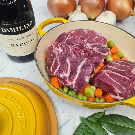 Pasture-raised heritage pork cheeks brasato prep in a yellow Le Creuset Dutch oven with carrots, celery, onions, bay leaves, and Barolo — Wishbone Heritage Farms, Saint George, SC