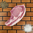 Pasture-raised heritage breed thick-cut center cut pork chop on an end-grain butcher block with flake salt and cracked pepper — Wishbone Heritage Farms, Saint George, SC