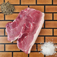 Pasture-raised heritage breed sirloin cut pork chop on an end-grain butcher block with flake salt and cracked pepper — Wishbone Heritage Farms, Saint George, SC