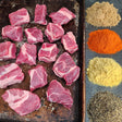 Pasture-raised heritage breed pork for stew on a seasoned sheet pan with dry rub spices — brown sugar, paprika, mustard, and black pepper — Wishbone Heritage Farms, Saint George, SC