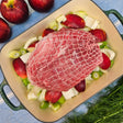 Raw pasture-raised heritage breed pork fresh outside ham, boneless and netted, on apples and fennel in a green roasting pan — Wishbone Heritage Farms, Saint George, SC