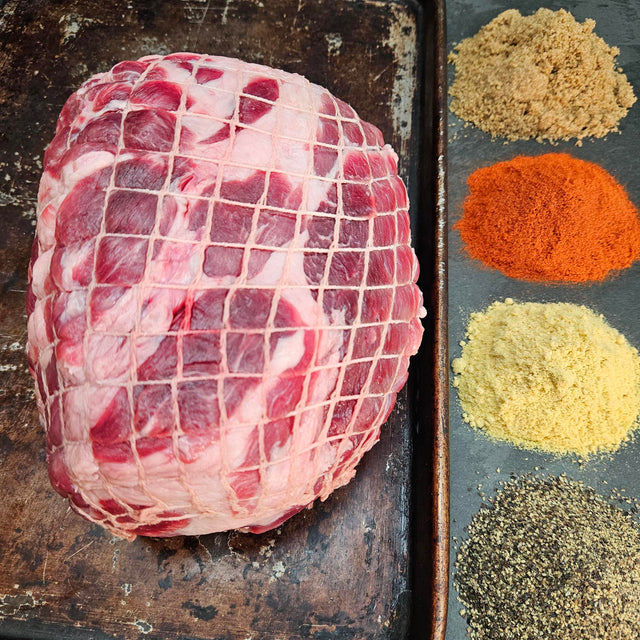 Pasture-raised heritage breed pork picnic shoulder on a seasoned sheet pan with dry rub spices — brown sugar, paprika, mustard, and black pepper — Wishbone Heritage Farms, Saint George, SC