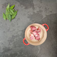 Pasture-raised heritage breed pork pig tail in a red Le Creuset Dutch oven with fresh bay leaves — Wishbone Heritage Farms, Saint George, SC