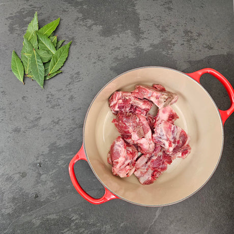 Pasture-raised heritage breed pork soup bones in a red Le Creuset Dutch oven with fresh bay leaves — Wishbone Heritage Farms, Saint George, SC